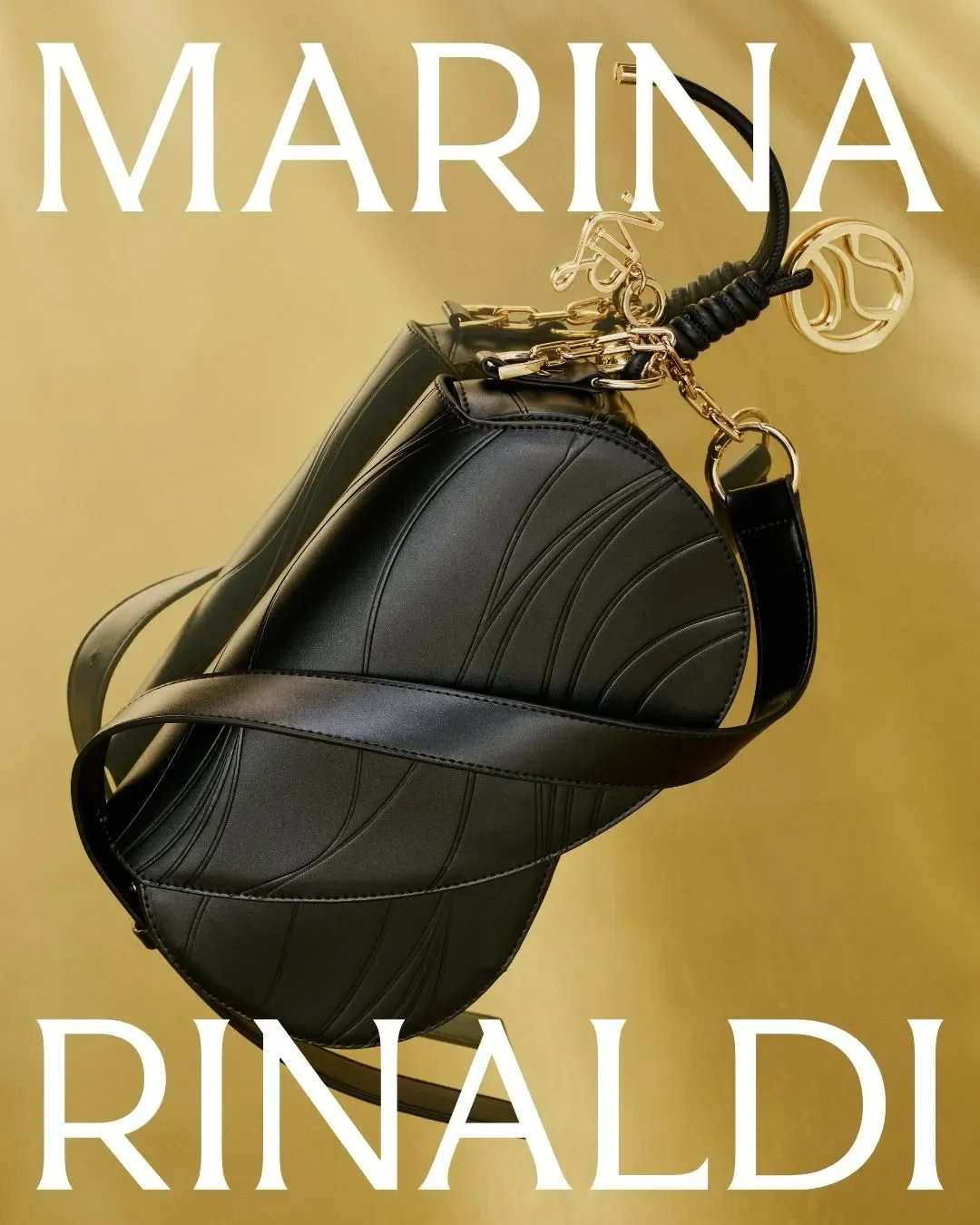 Fotografia still life editoriale della borsa in pelle nera Marina Rinaldi con lavorazione a onde e charm dorati, posizionata su uno sfondo oro satinato con titolazione grafica del brand.