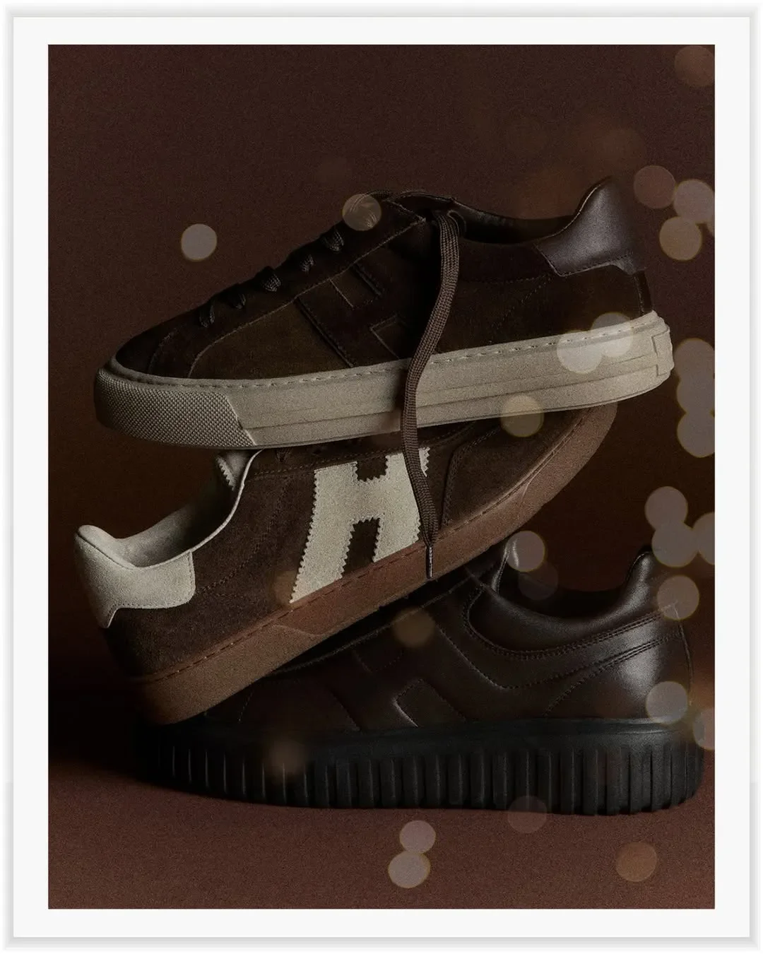 Set design e props styling per scatto still life di calzature Hogan. Pila in equilibrio di tre sneakers in camoscio marrone su sfondo ton sur ton con effetti bokeh