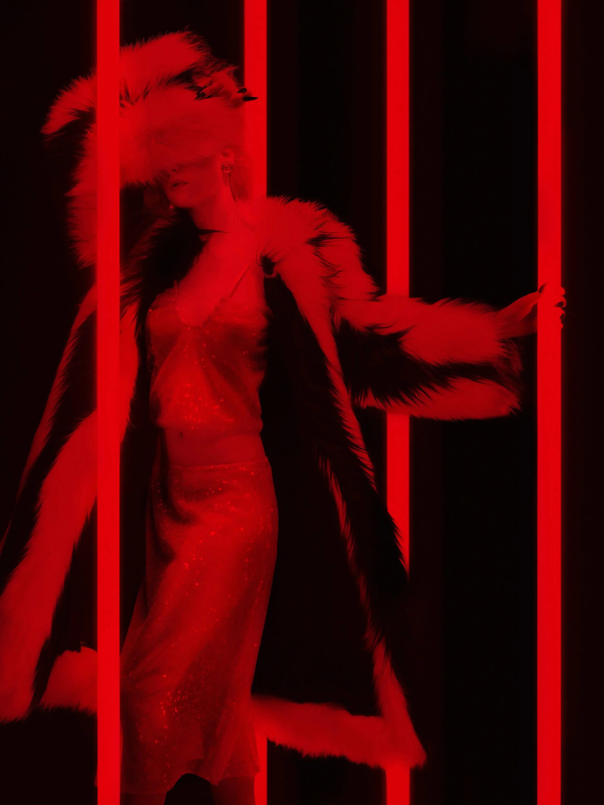 Scatto moda d'atmosfera immerso in un'intensa luce rossa per DNA Magazine in collaborazione con Gucci. Modella incorniciata da barre di luce neon rosse verticali, con indosso uno scenografico cappotto in pelliccia con cappello coordinato ad alto volu