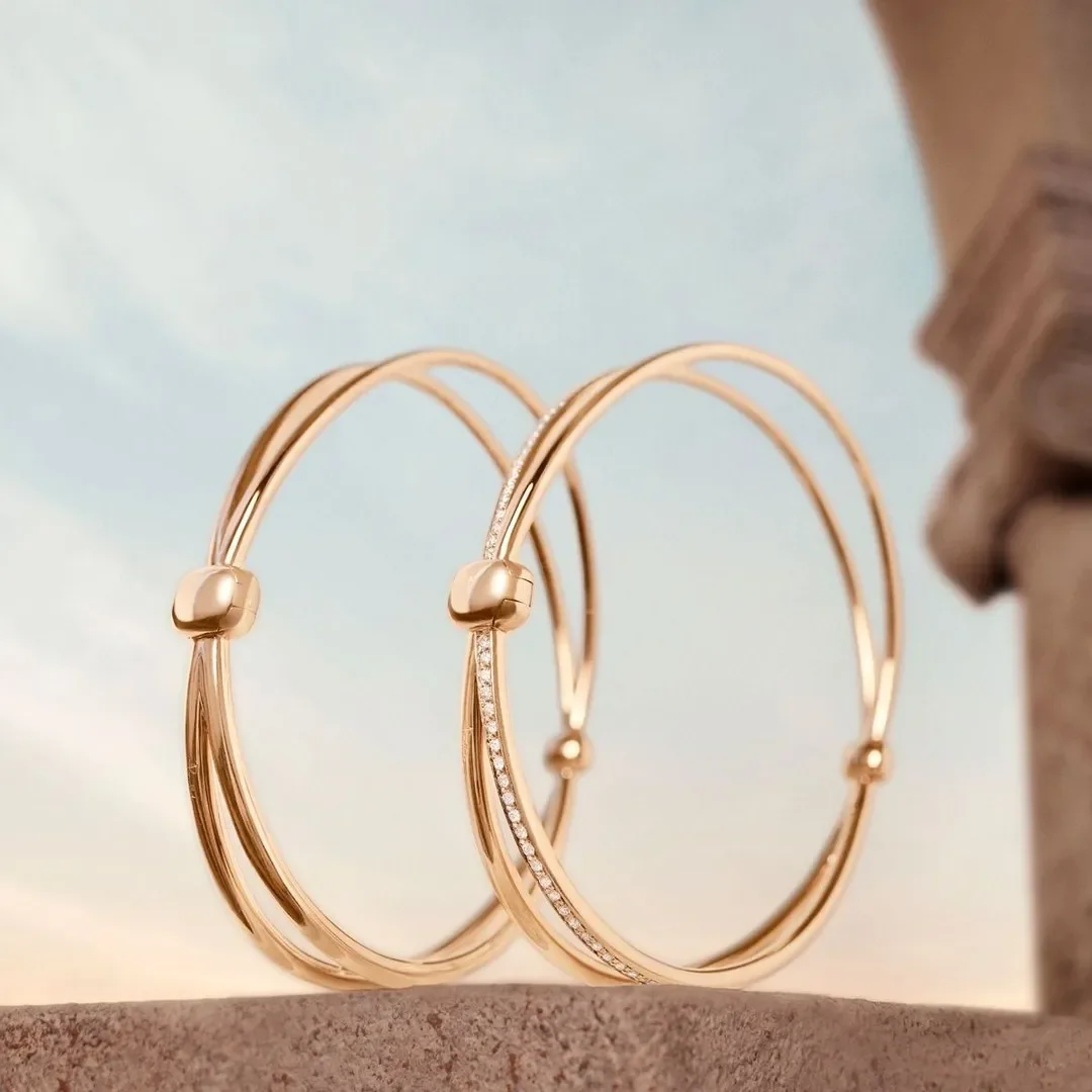 Progetto di set design per la campagna ADV gioielli Pomellato. Bracciali rigidi in oro e diamanti posizionati su un elemento scenografico in pietra con arco architettonico in background.