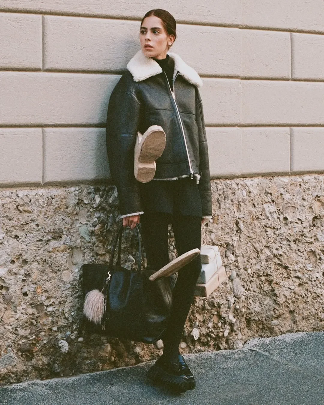 Scenografia outdoor e props design per la campagna pubblicitaria Hogan. Modella con giacca in montone, tote bag in pelle nera, pacchi regalo e sculture artigianali in carta da imballo.