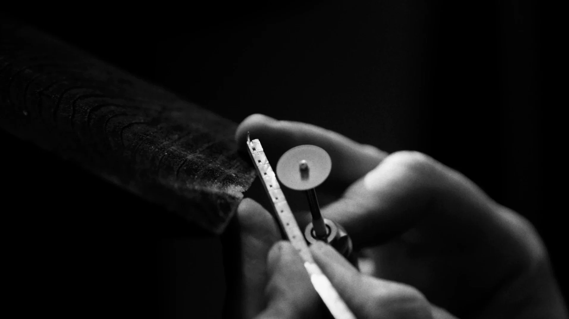 Dettaglio in bianco e nero delle mani di un maestro orafo durante la lavorazione e lucidatura artigianale di un gioiello per la collezione Ralph Lauren High Jewelry.