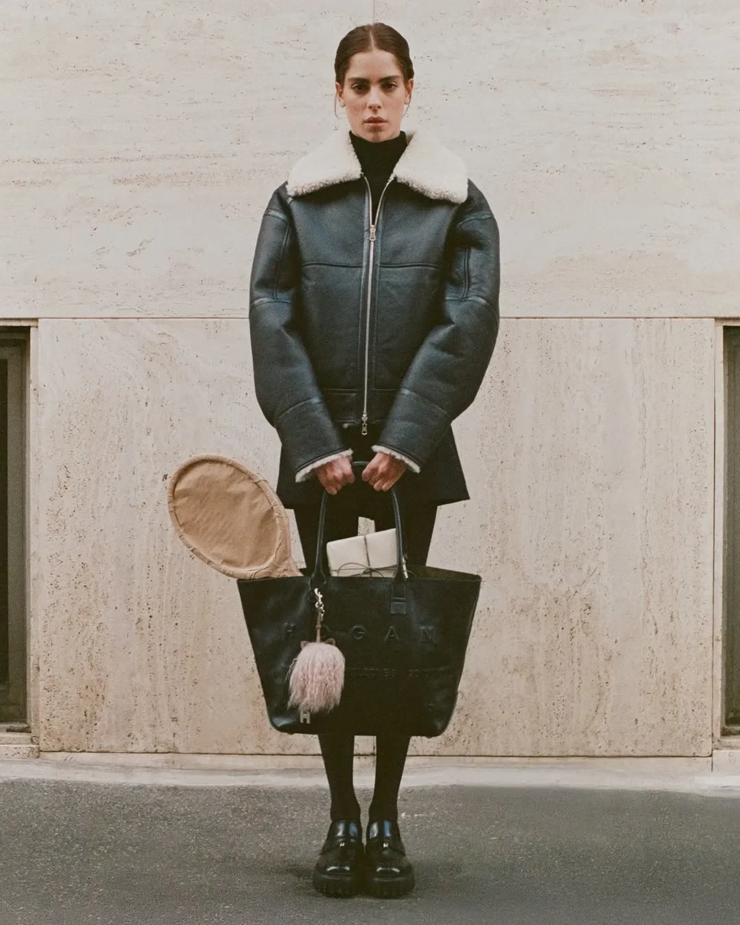 Scenografia e props styling per la campagna ADV Hogan. Modella con giacca in montone e borsa tote in pelle nera contenente una racchetta da tennis impacchettata in carta.