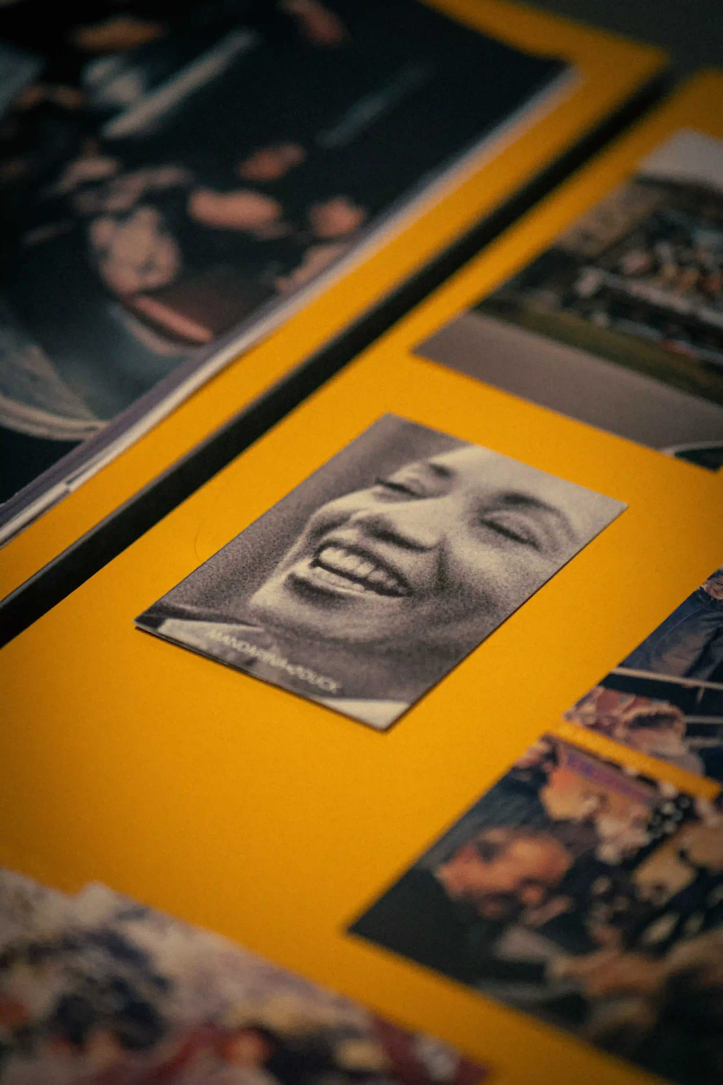 Dettaglio ravvicinato del moodboard per l'evento Mandarina Duck a Berlino, con ritratti d'archivio in bianco e nero allestiti su fondo giallo iconico del brand.