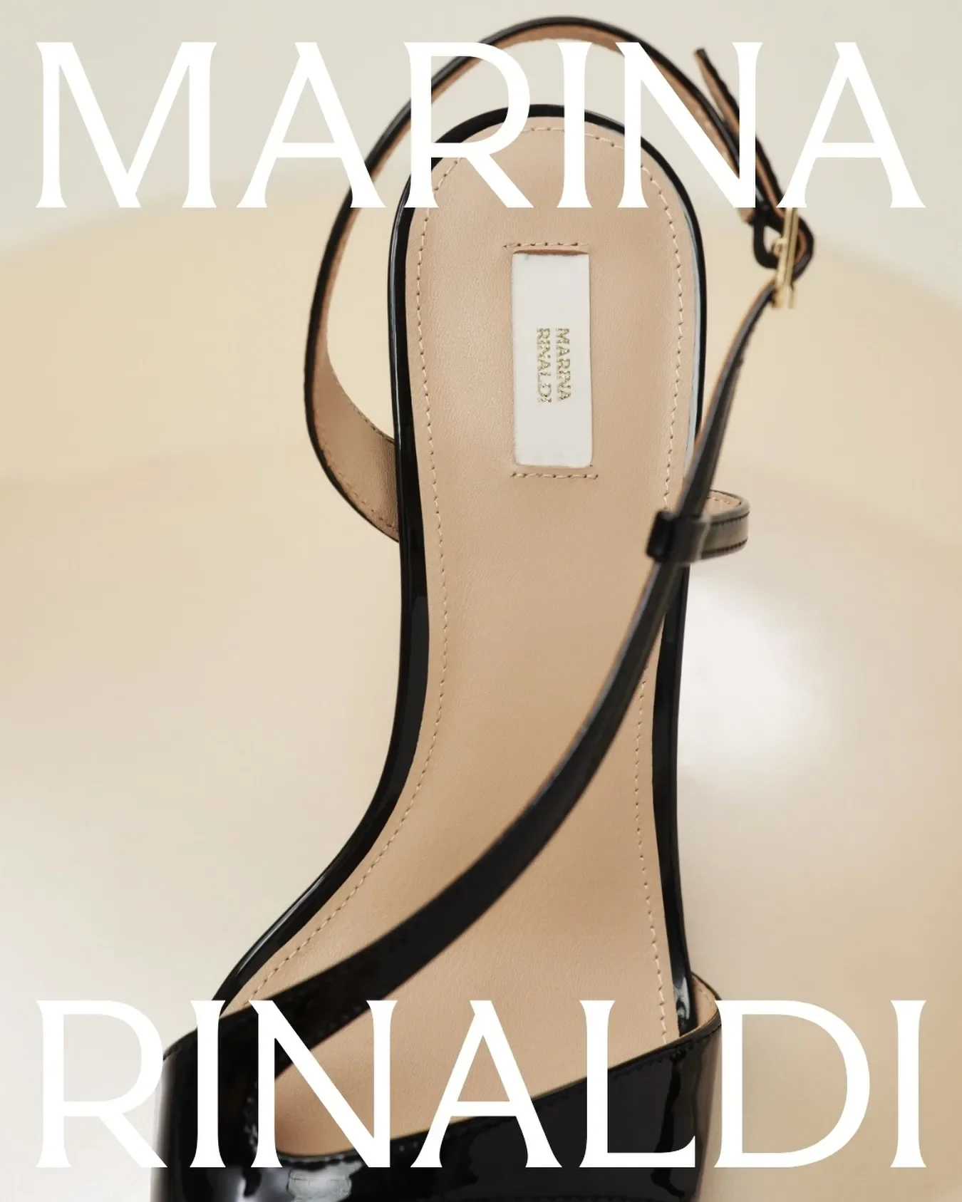 Dettaglio ravvicinato di una decolleté slingback in vernice nera con cinturino sottile, inserita nel set della sfilata Marina Rinaldi con sovrapposizione grafica del logo