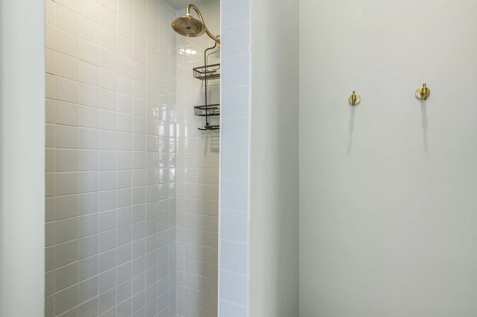 Mollie Walters House upstairs bathroom shower with celadon-colored tiles and a brass showerhead