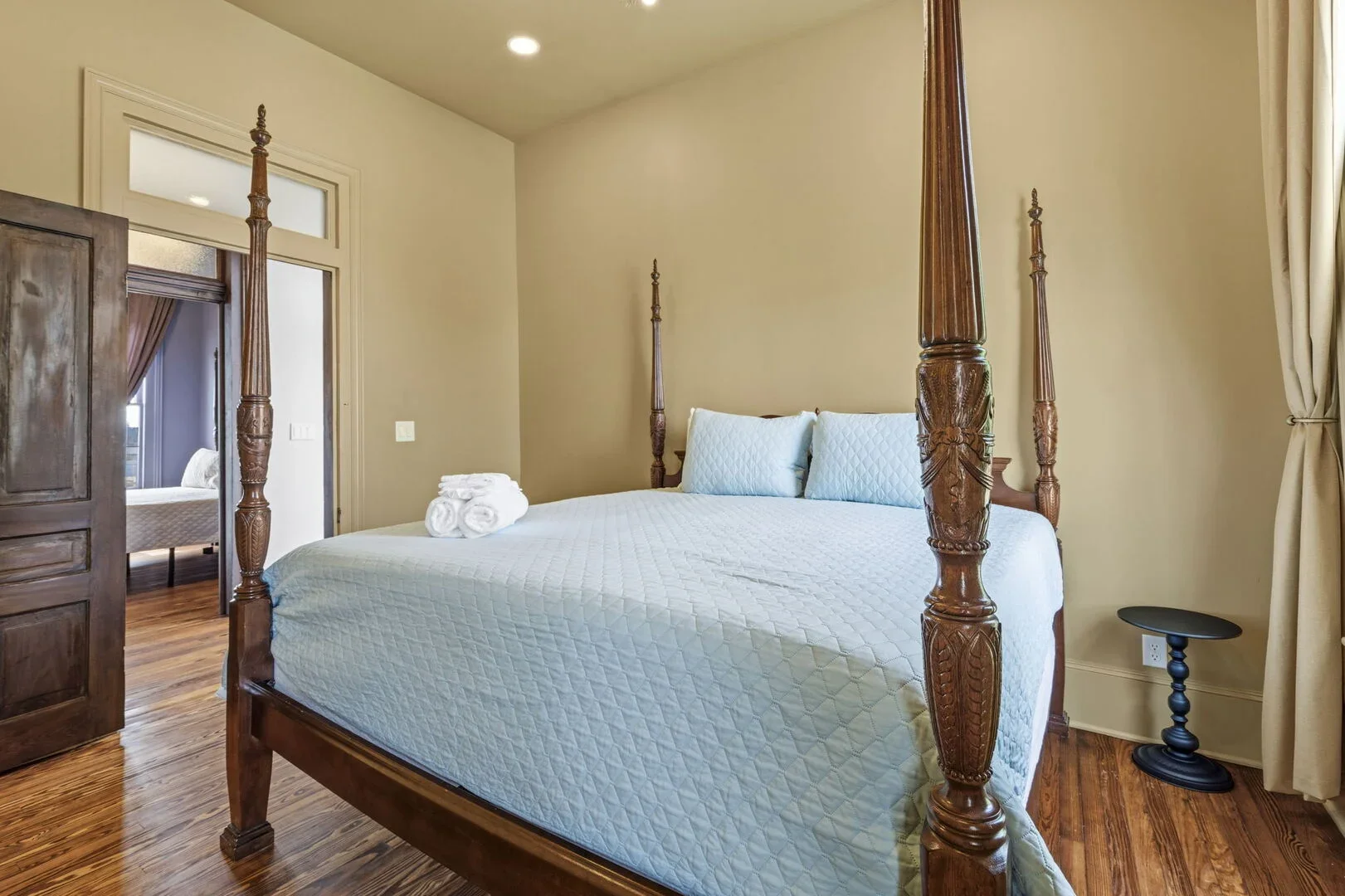Golden Chamber in the restored 1886 Mollie Walters House with a wooden four-poster bed, a small black side table, and armoire