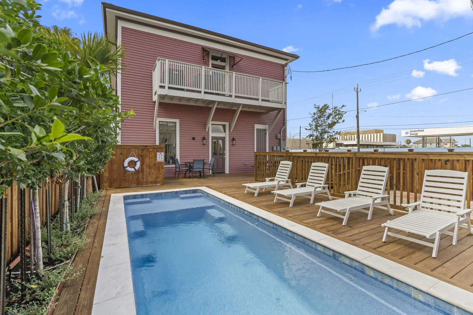 Mollie Walters House backyard with a swimming pool surrounded by a wooden deck and white lounge chairs