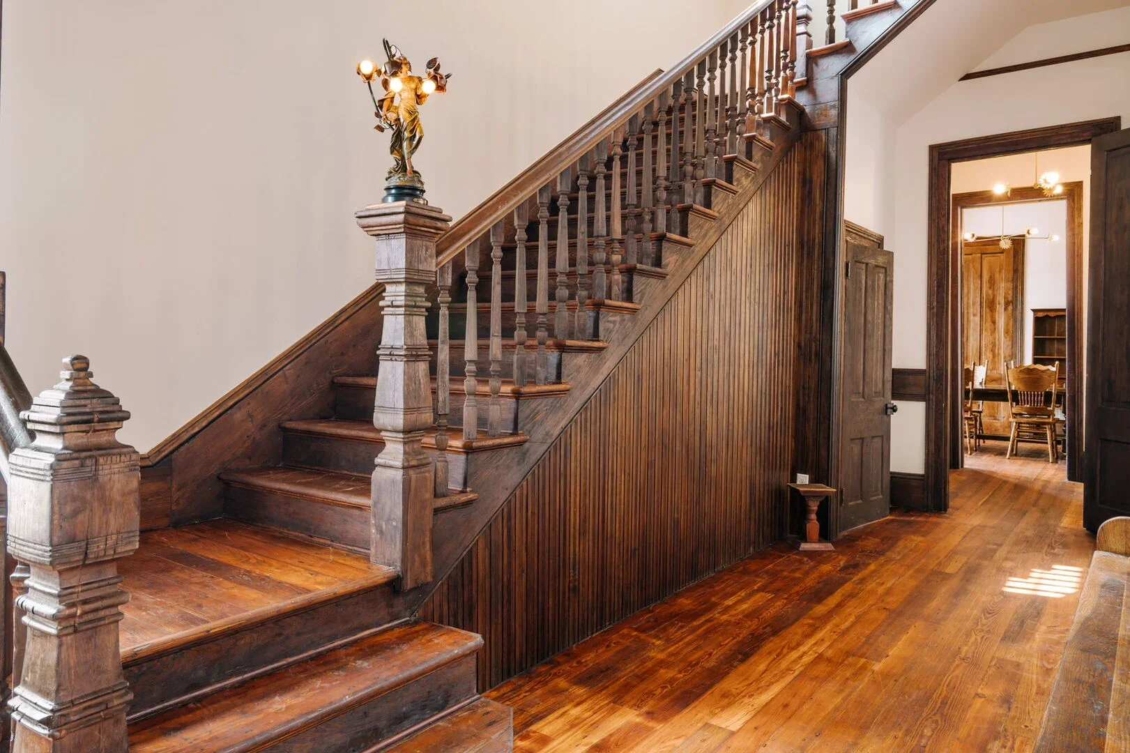 Mollie Walters House restored wood staircase, a decorative light fixture on top of a post, and wooden floors