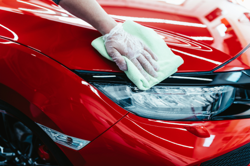 Hand applicating ceramic coat to paint surface on red vehicle during full detail service
