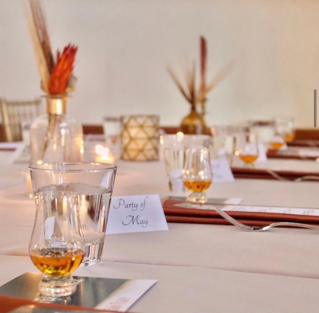 A banquet table decorated with vases, candles, and place cards for a party in May.