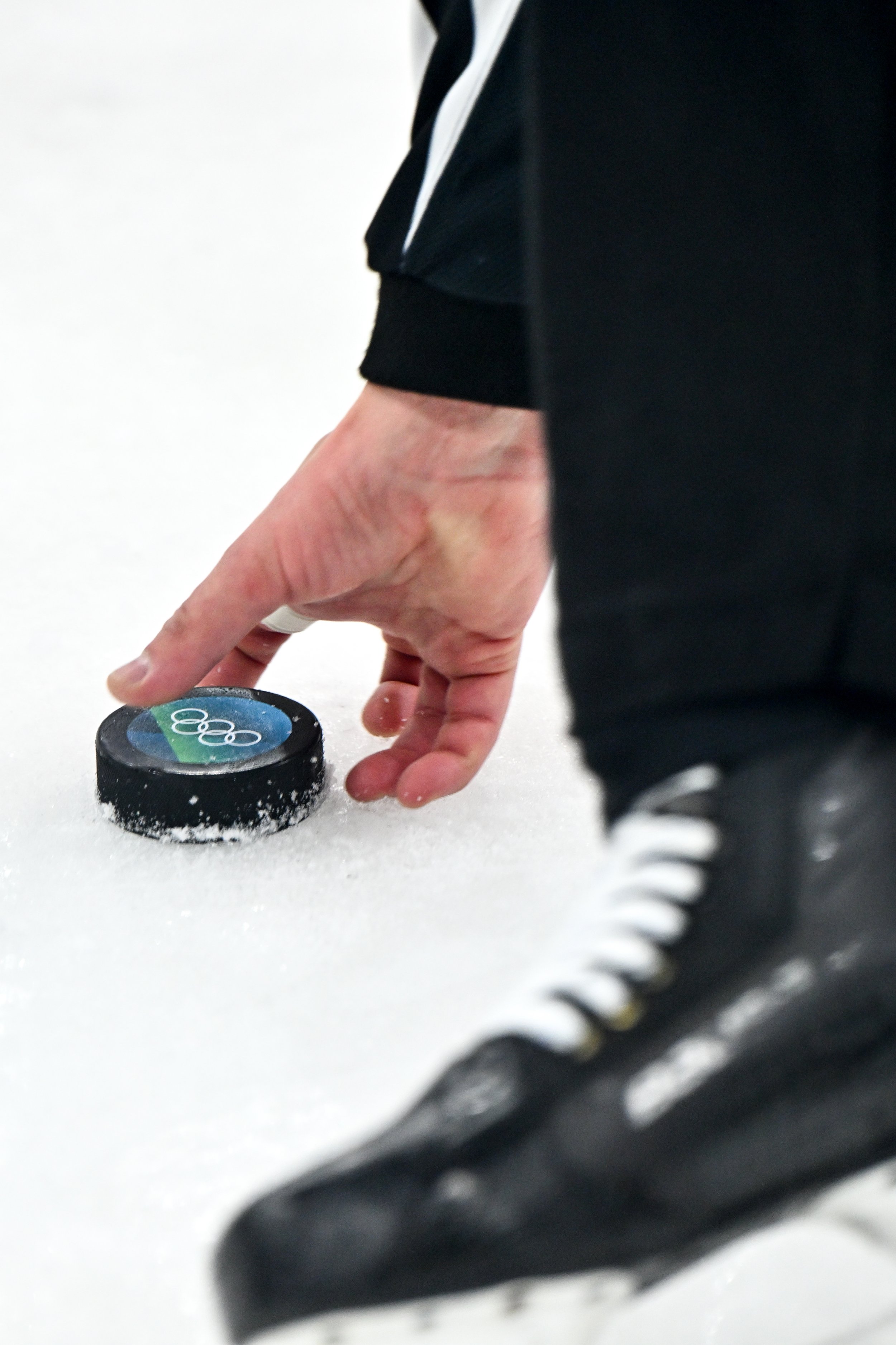  The referee picks up the puck bearing the Olympic logo 