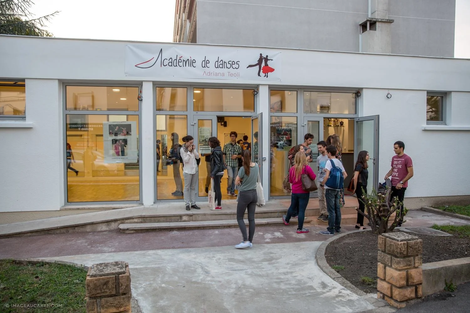 Groupe de personnes devant l'entrée d'une école de danse appelée 'Académie de danses Adriana Teoli'