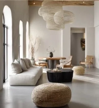 Salon moderne avec canapé beige, fauteuils en bois, poufs, suspension en corde, et grande fenêtre