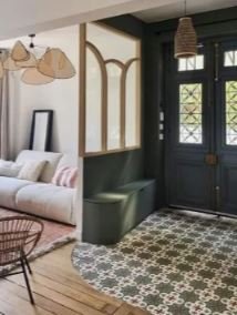 Intérieur d'une salle avec un canapé blanc, un panneau décoratif, une banquette verte et une porte en bois bleu foncé avec des fenêtres