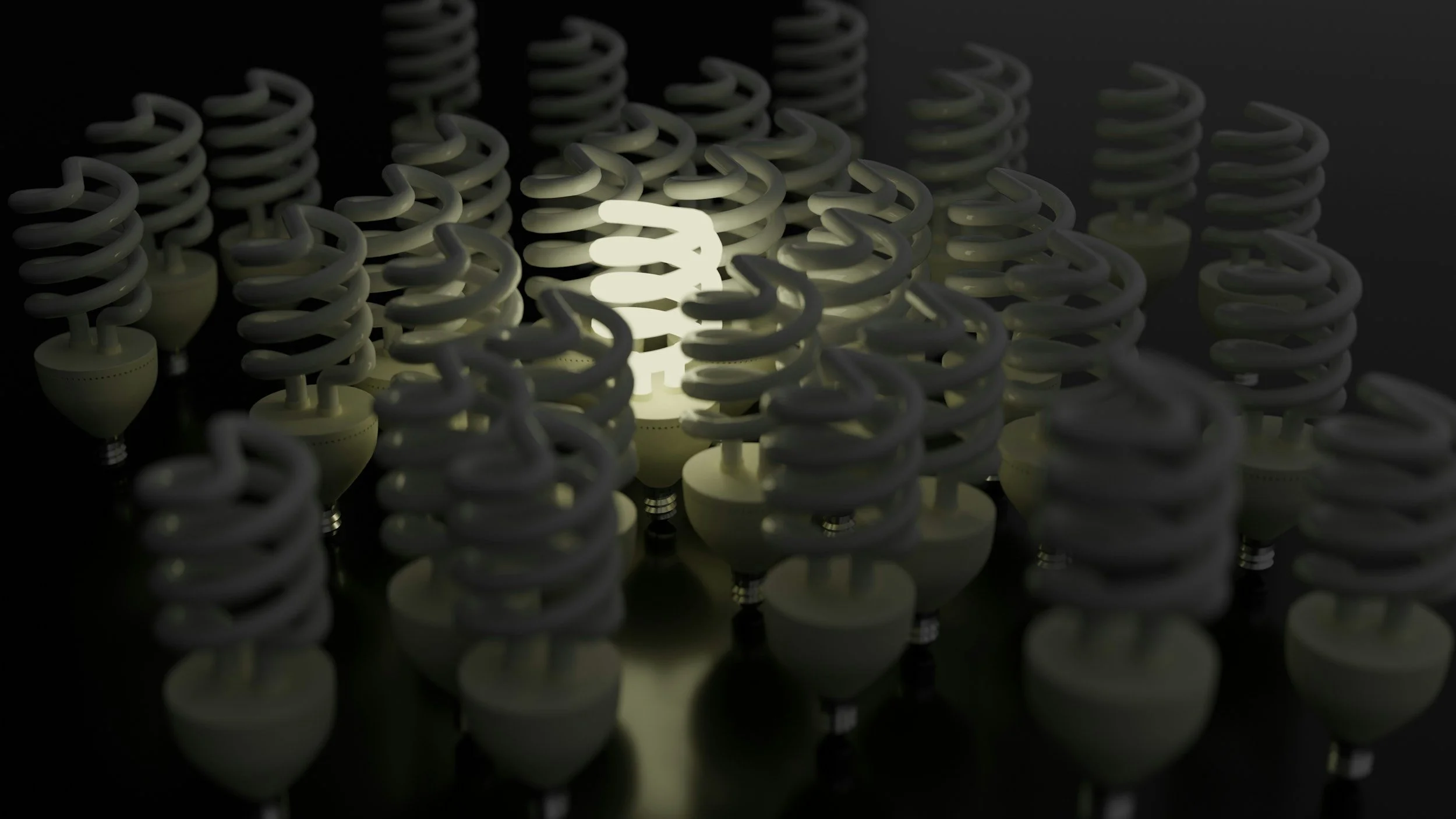 A close-up view of multiple white light bulbs with spiral filaments, illuminated in a dark environment.