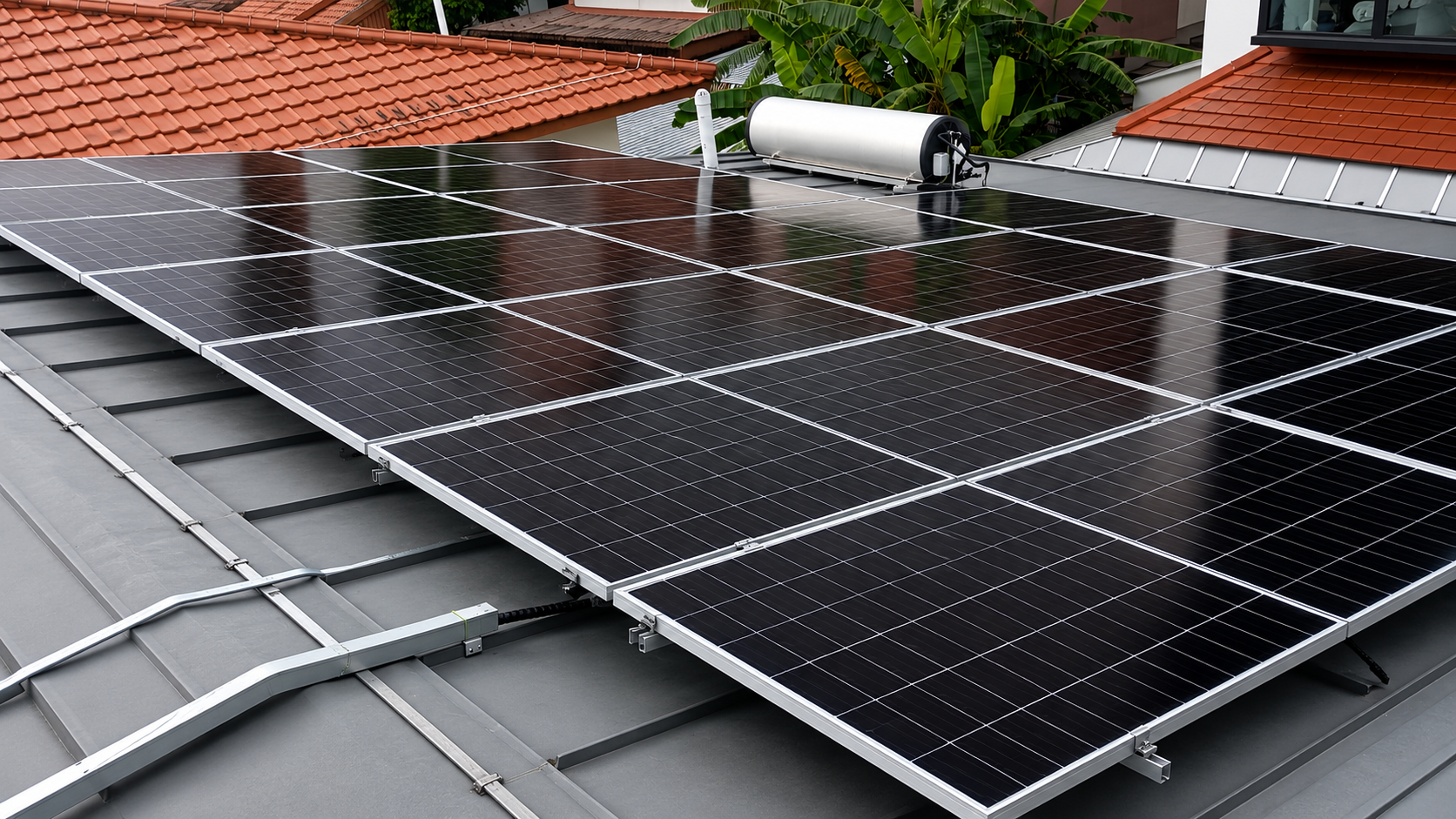 Solar panels installed on a building rooftop with a water tank and green plants in the background.