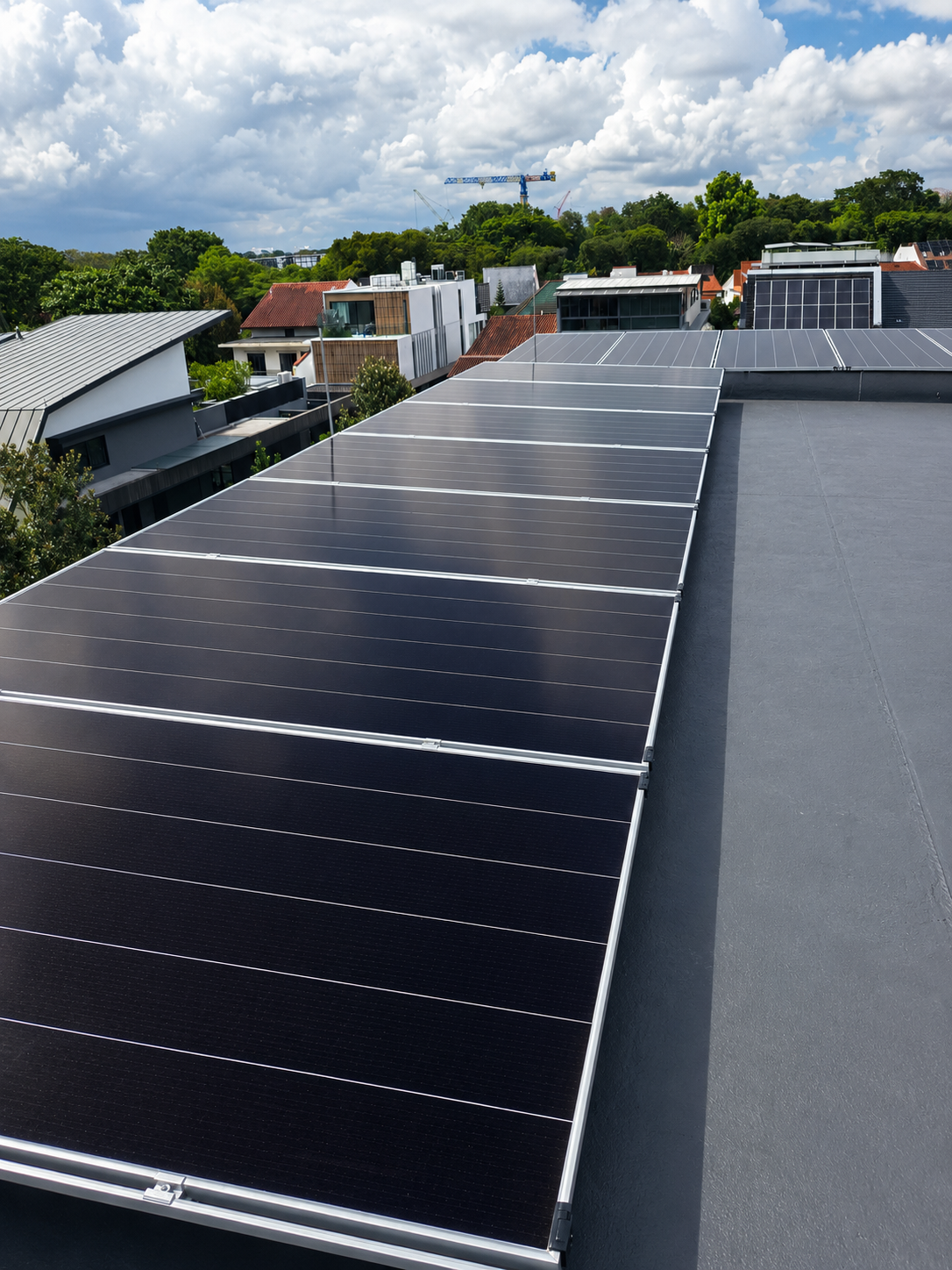 Rooftop with solar panels, residential neighborhood with houses and trees, cloudy sky.