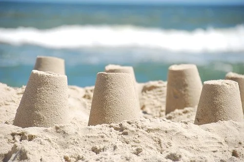 Sandcastles built on a beach with ocean waves in the background.