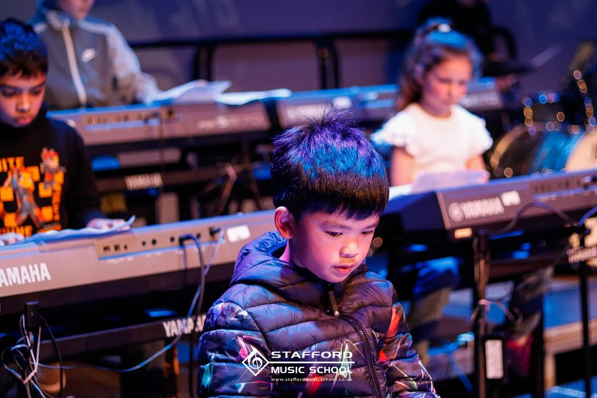 Children practicing on Yamaha keyboards during a music class at Stafford Music School.
