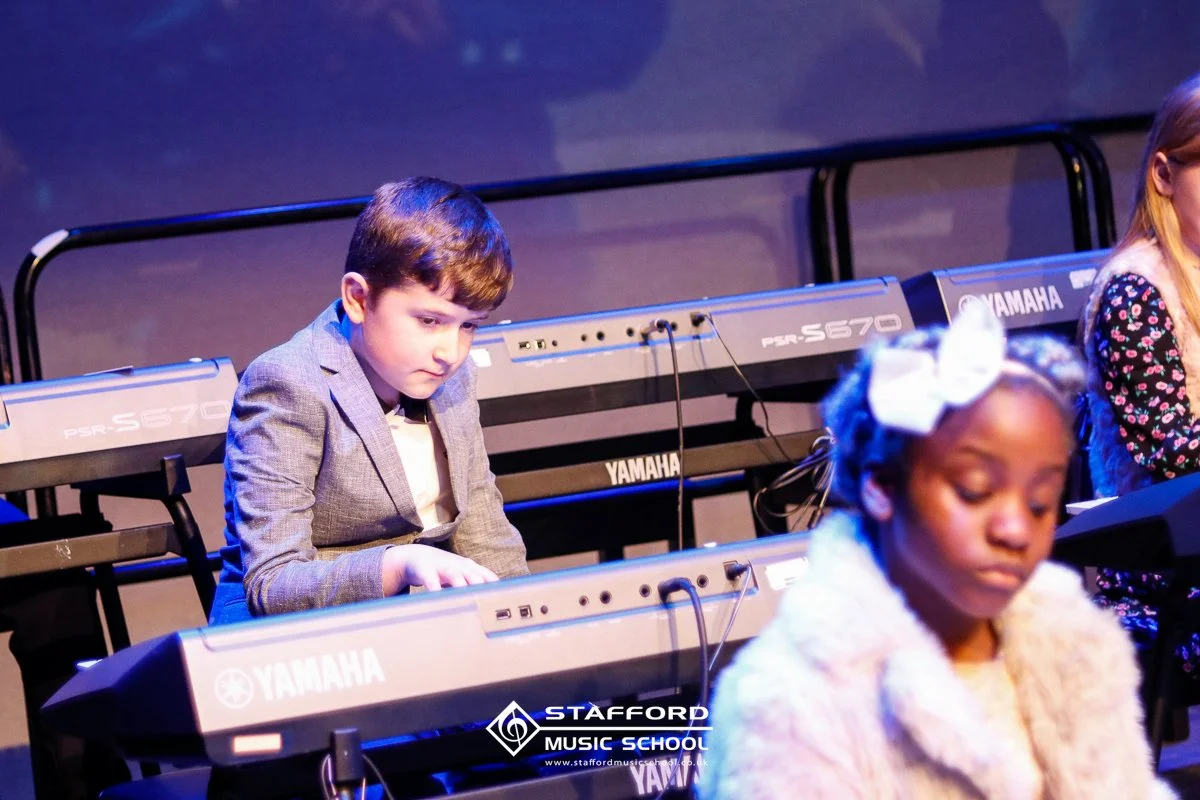 Children playing Yamaha keyboards during a music class at Stafford Music School.