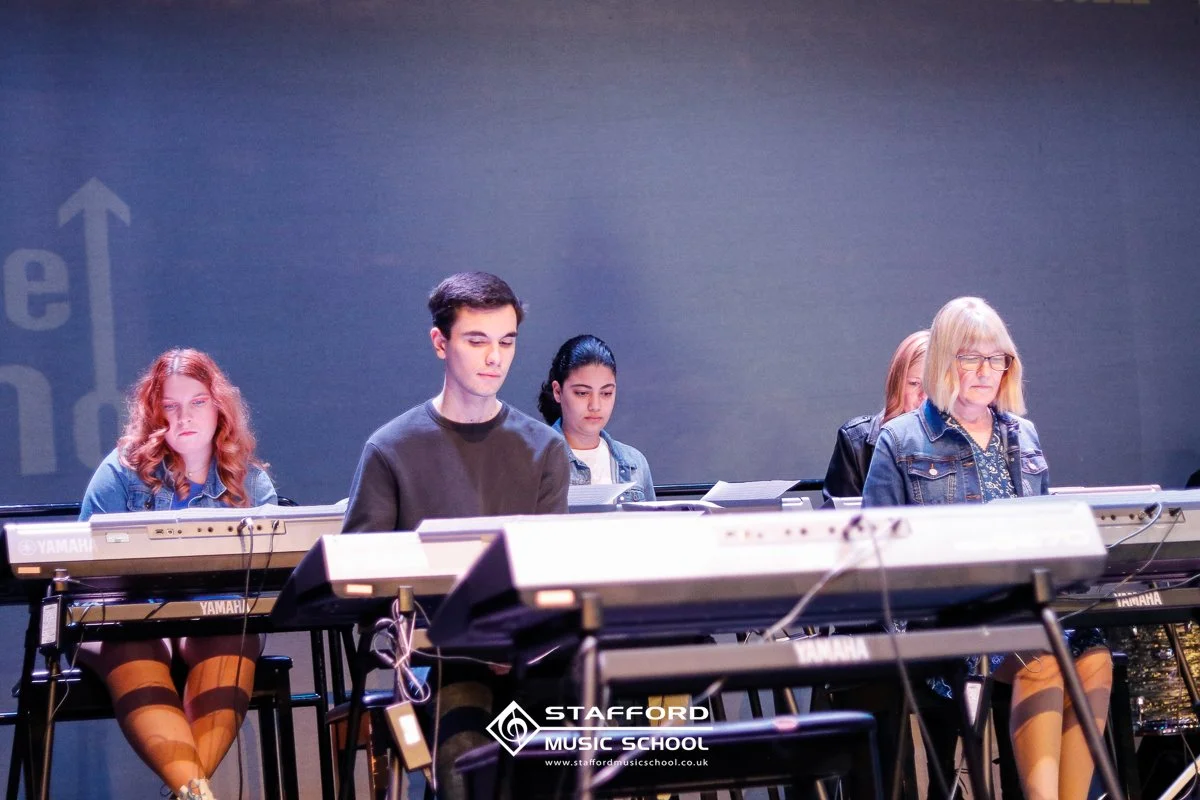 Group of students playing keyboards during a music performance at Stafford Music School.