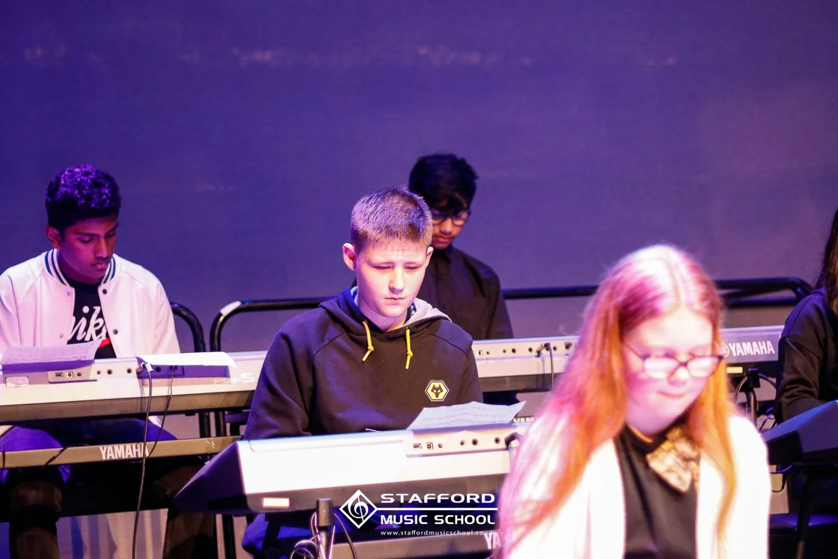 Students playing electronic keyboards during a music class at Stafford Music School.
