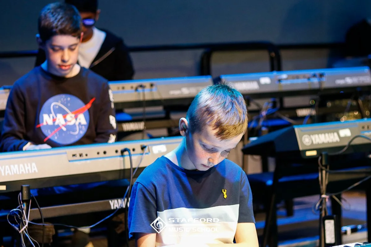 Kids playing electronic keyboard instruments on stage