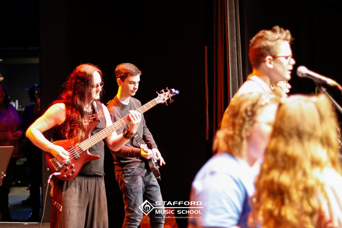 Two young musicians playing electric guitars on stage during a music class at Stafford Music School.