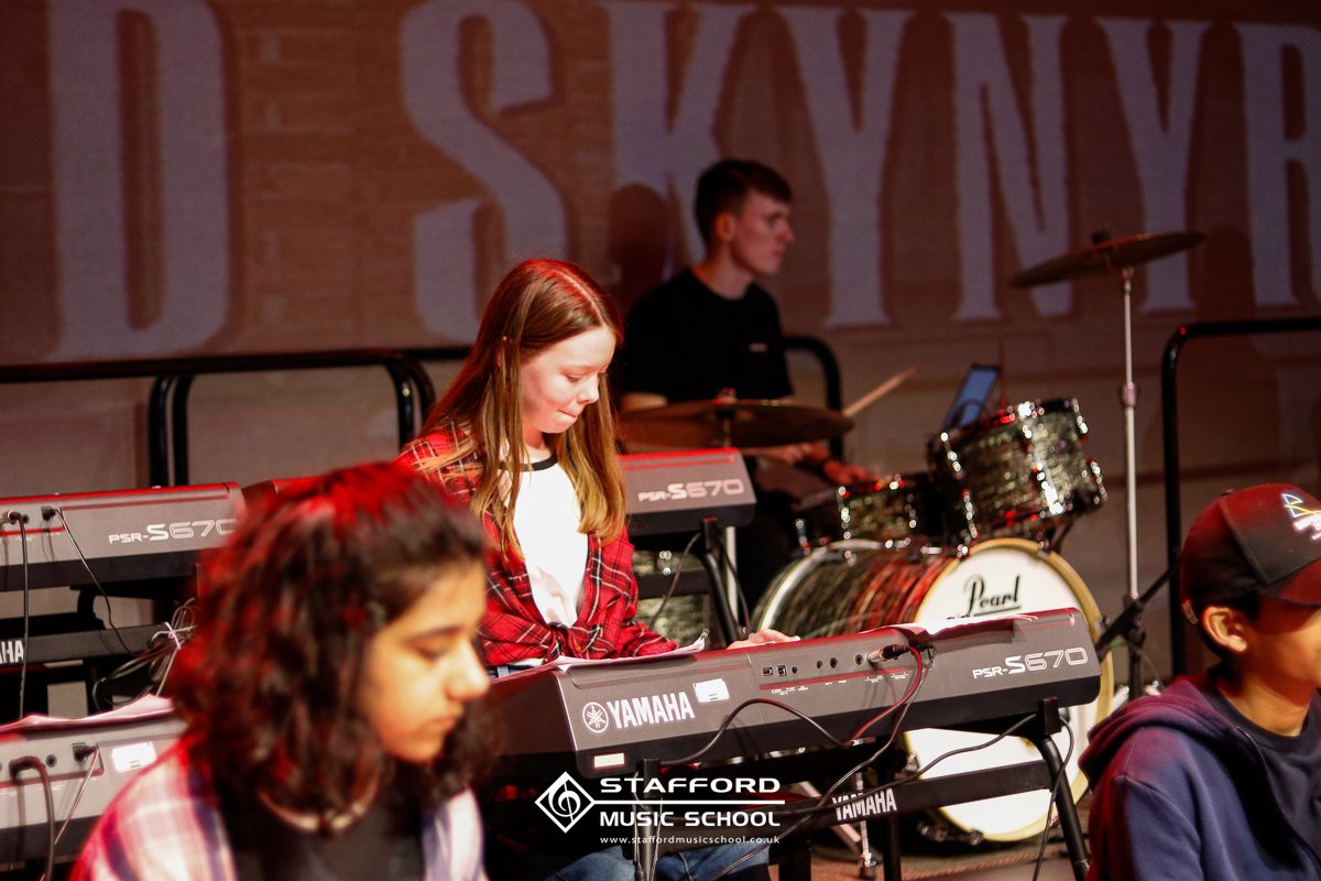 Young students playing keyboard and drums during a music practice or performance at Stafford Music School.
