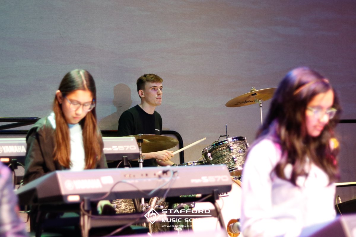 Musicians playing keyboard and drums during a performance at Stafford Music School.