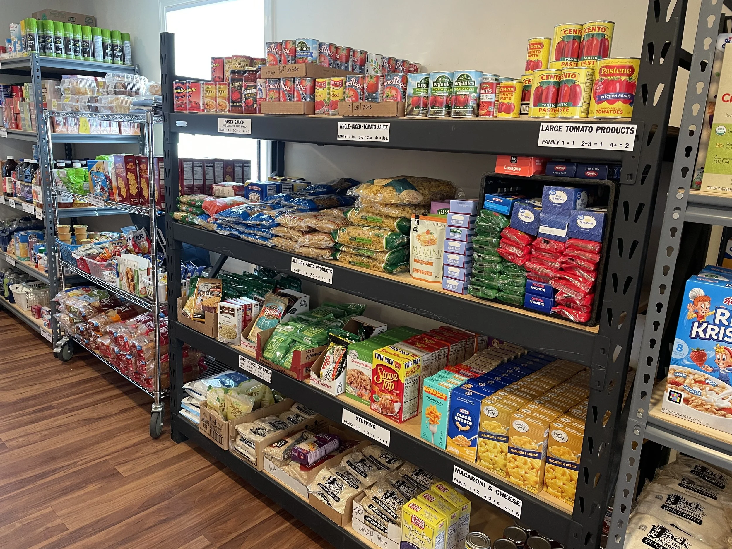 Shelf stocked with canned tomatoes, pasta sauces, and various pasta boxes in a grocery store aisle.
