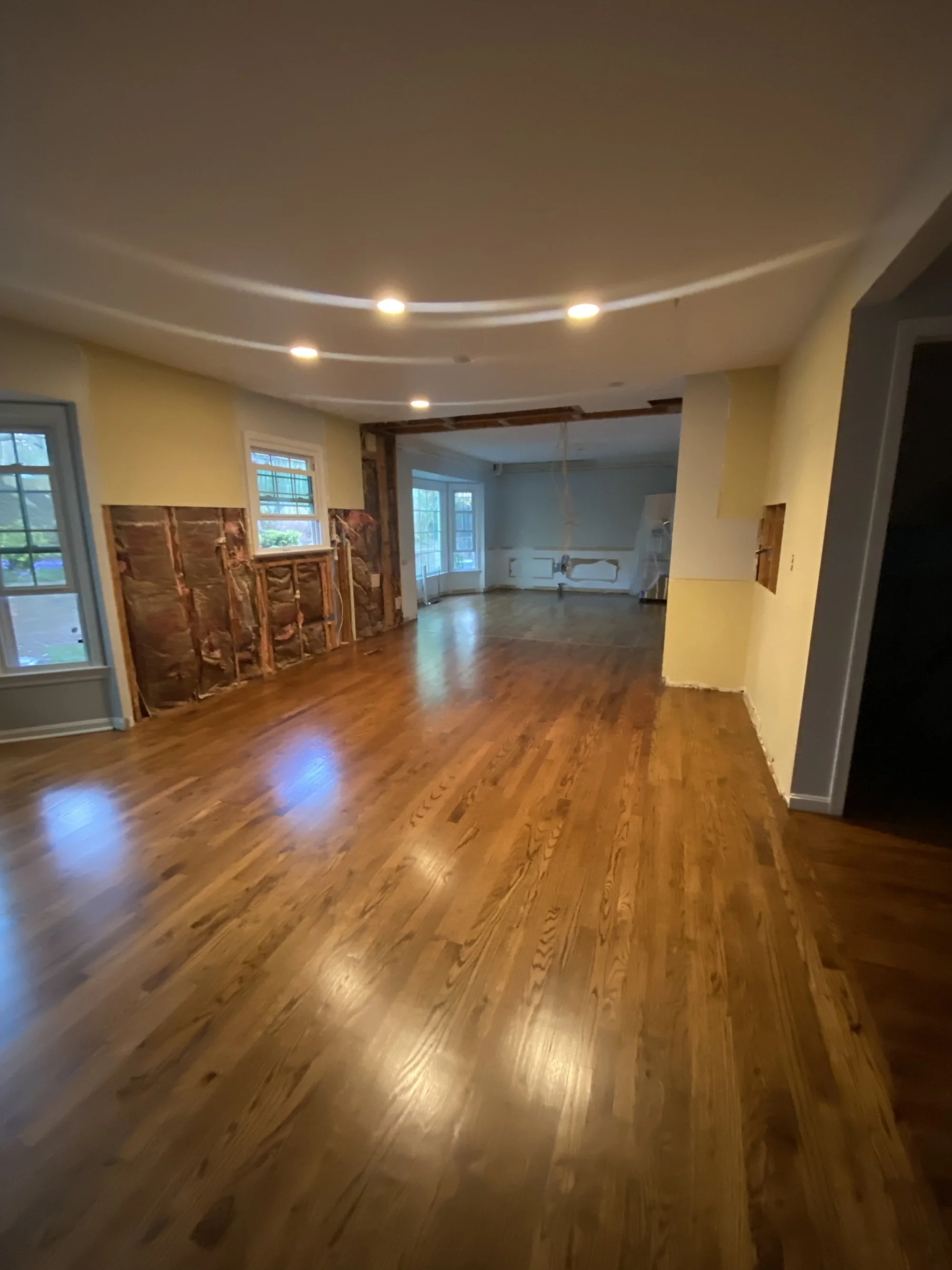 Interior room with hardwood floor, partially finished walls, and ceiling lights.