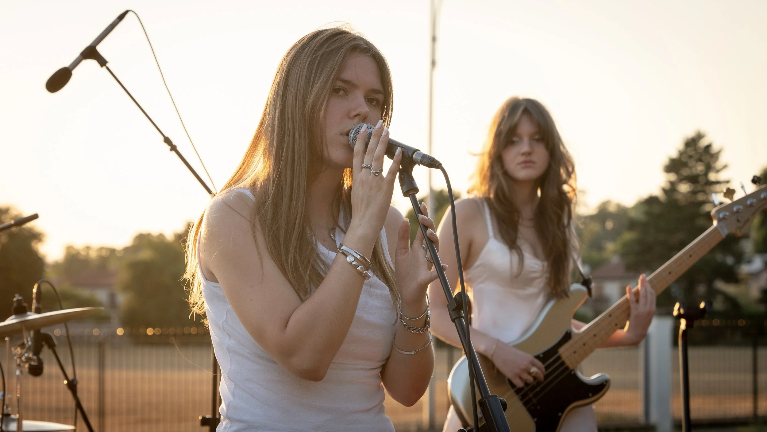 Deux jeunes femmes jouent de la musique lors d'un concert en extérieur au coucher de soleil.