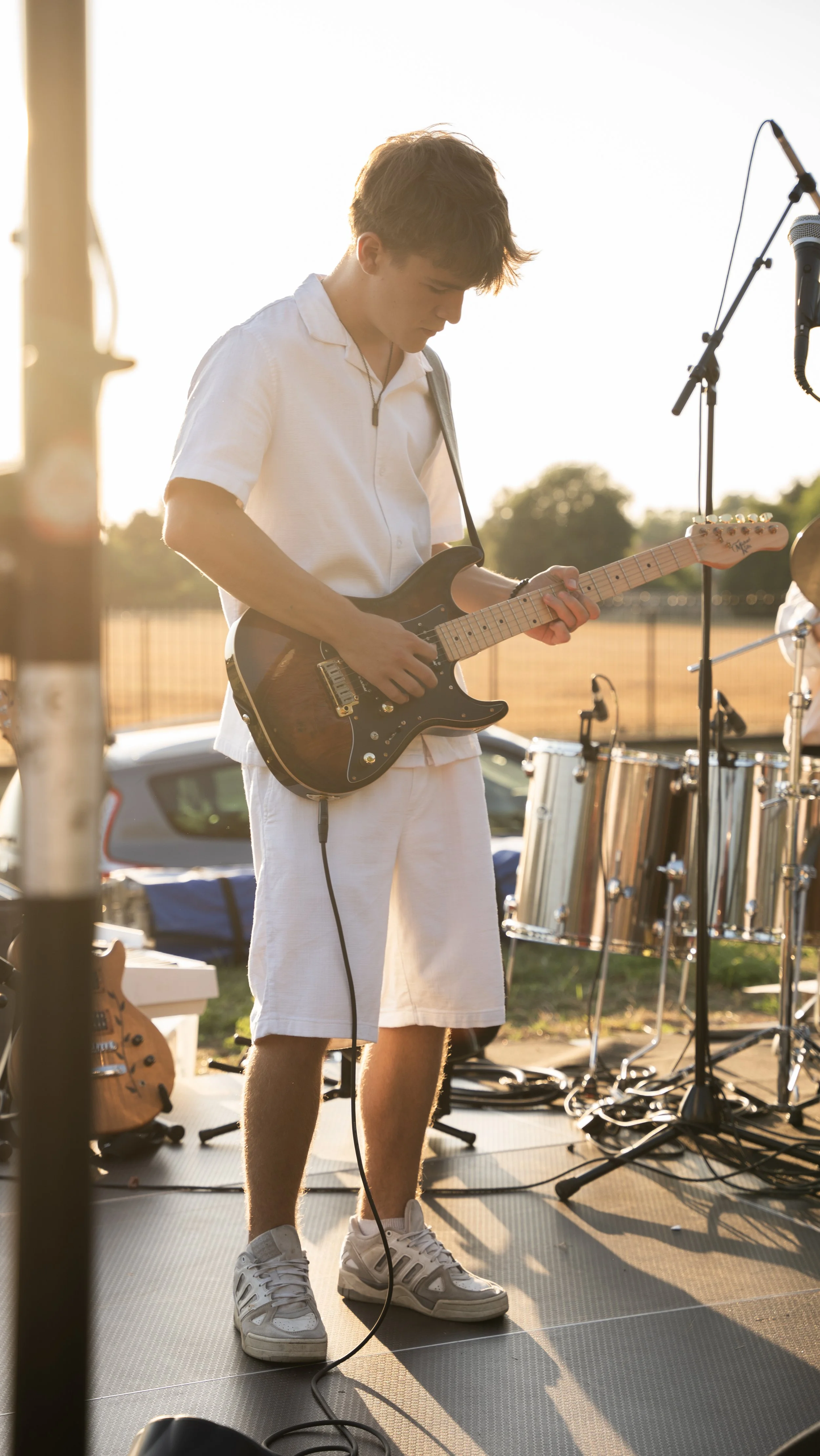 Jeune homme jouant de la guitare électrique lors d'une performance en plein air au coucher du soleil.
