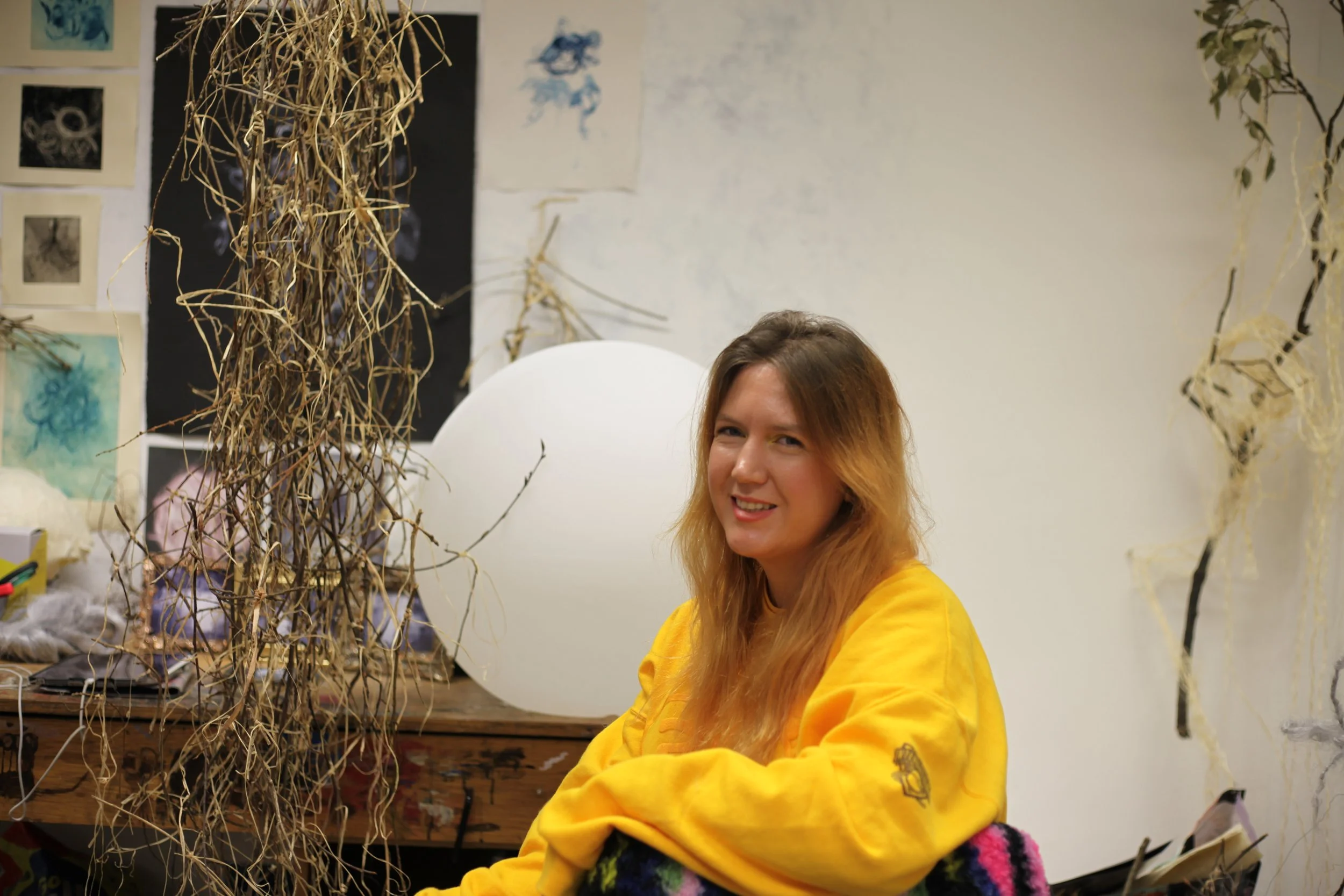 Image of artist Shannon Jade Wilson sitting at her desk in her studio at NCAD