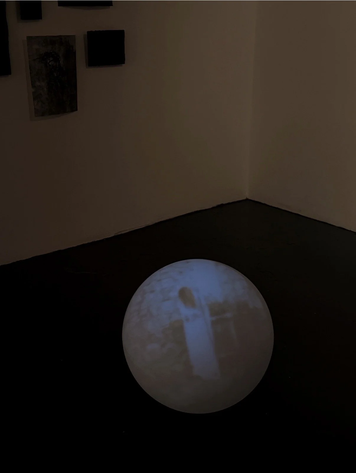 Image of an orb with a video projected on it, in the video there is a female figure in a white dress in a cemetary
