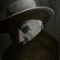 Black and white photo of an elderly person wearing a hat, peeking over a dark object, with one eye visible and a partially hidden face.