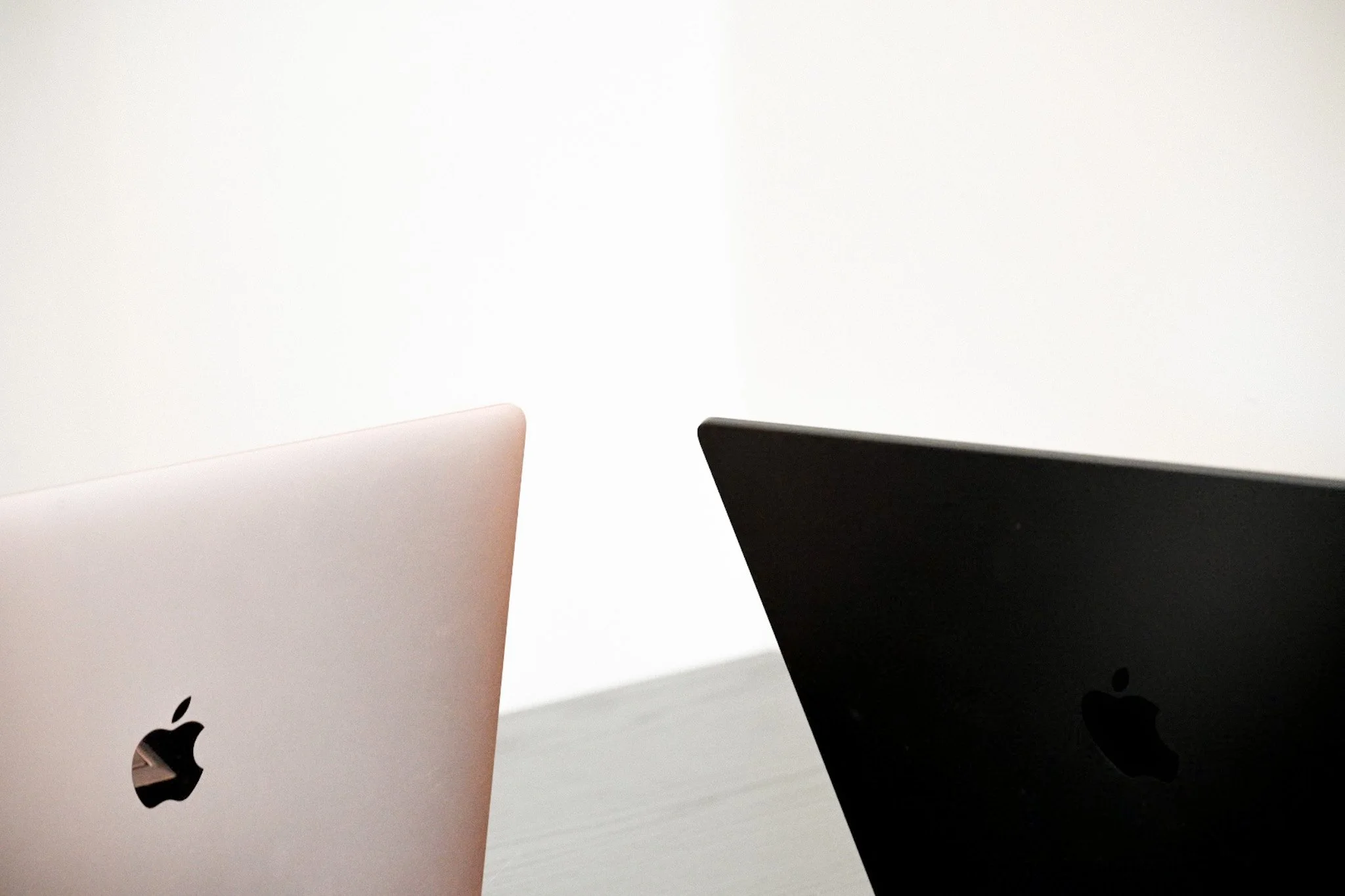 Two Apple MacBook laptops, one in space gray and the other in rose gold, placed on a white surface.