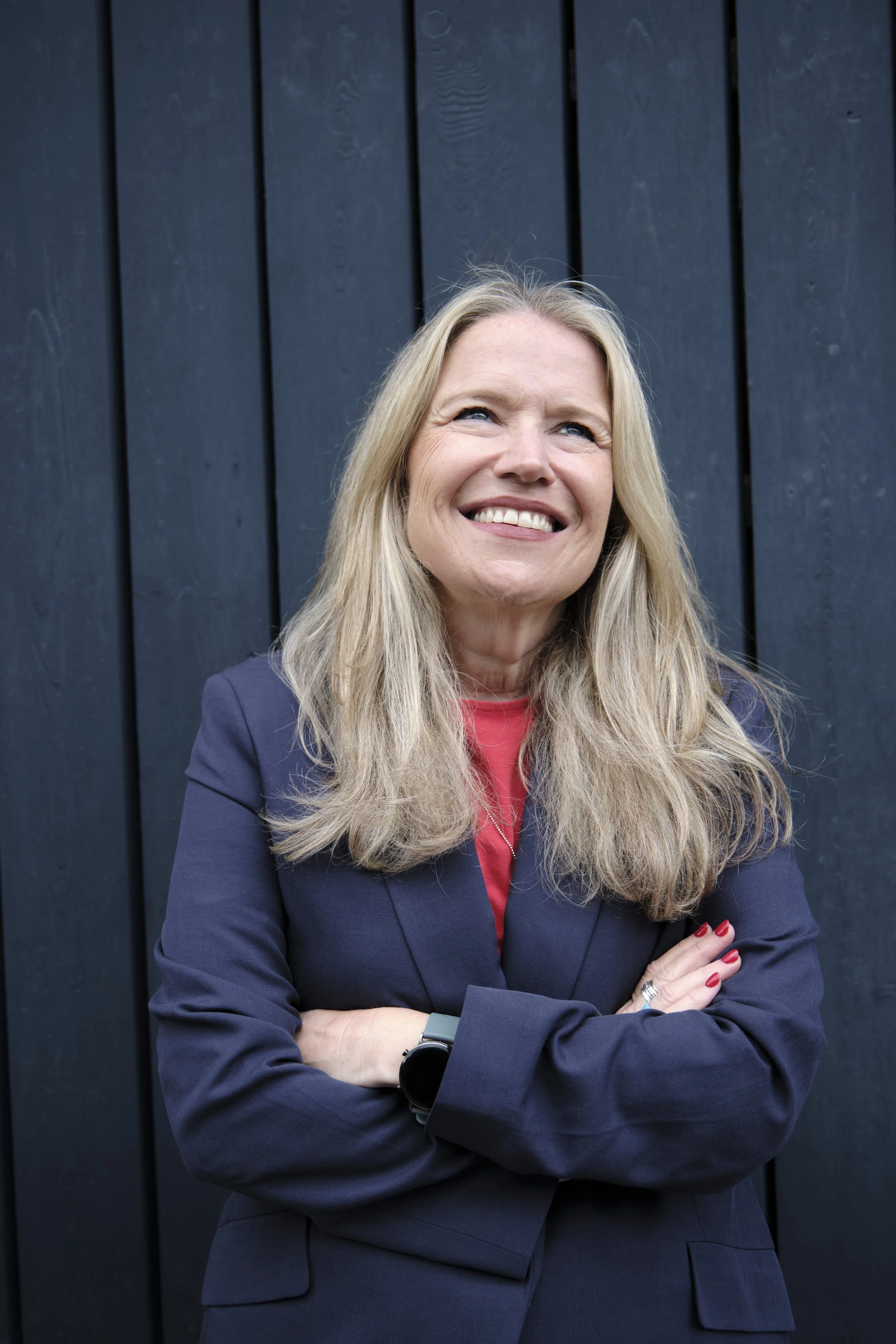 Debbie Porter standing with arms crossed against a dark wooden background.