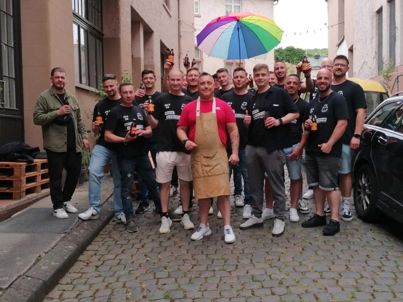 Ein Mann mit schwarzen Haaren sitzt auf einer Bank in einem hellen Raum, trägt eine blaue Pullover und bequeme beige Hosen, blickt nach rechts, während er die Hand auf die Bank stützt.