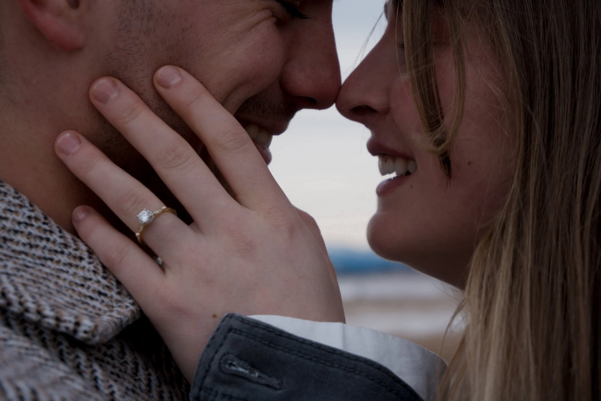 Newly engaged couple touching foreheads and smiling, her engagement ring visible, mountain engagement session in Kananaskis