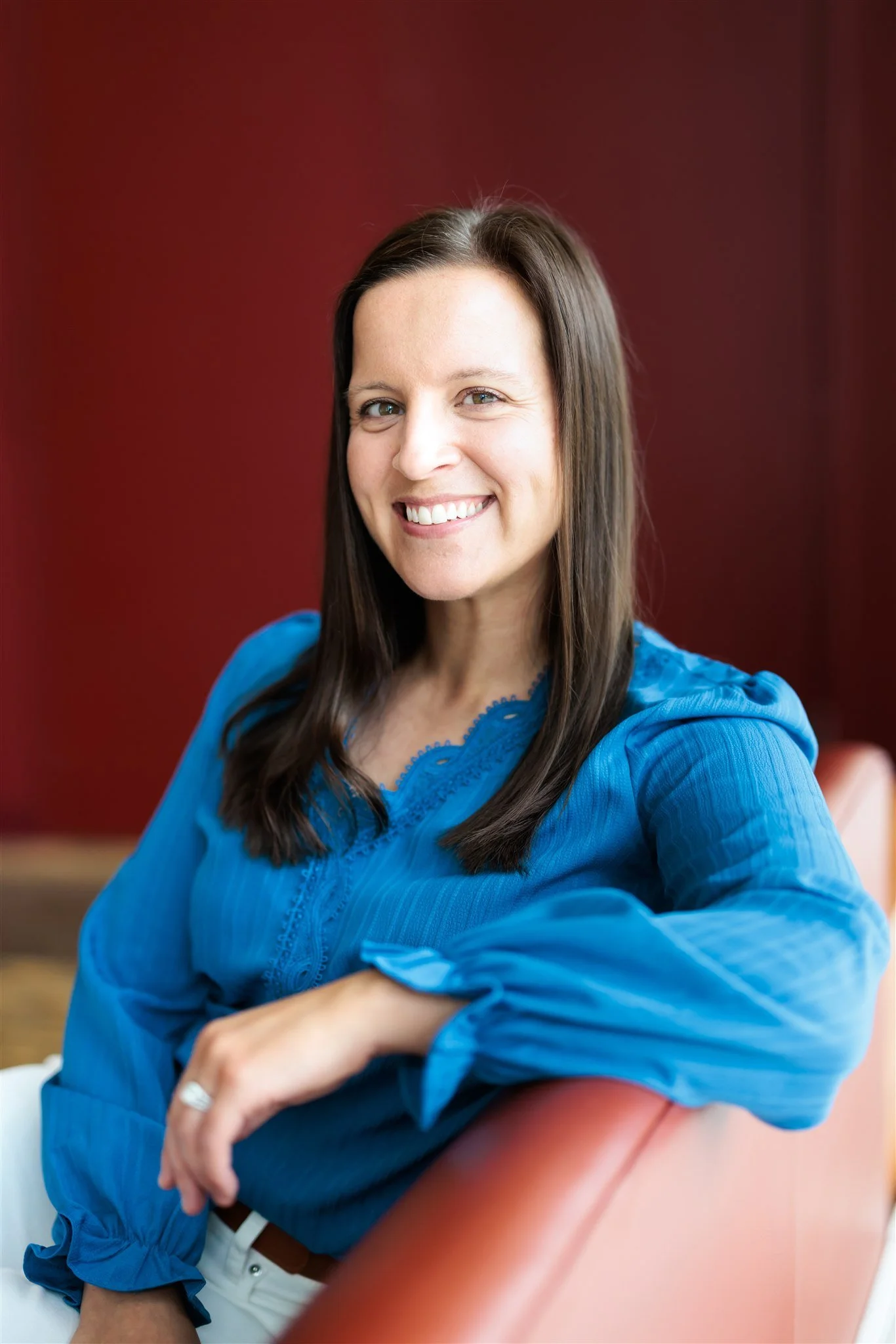 Headshot of Dr. Erica Behrens in a blue top sitting on a chair