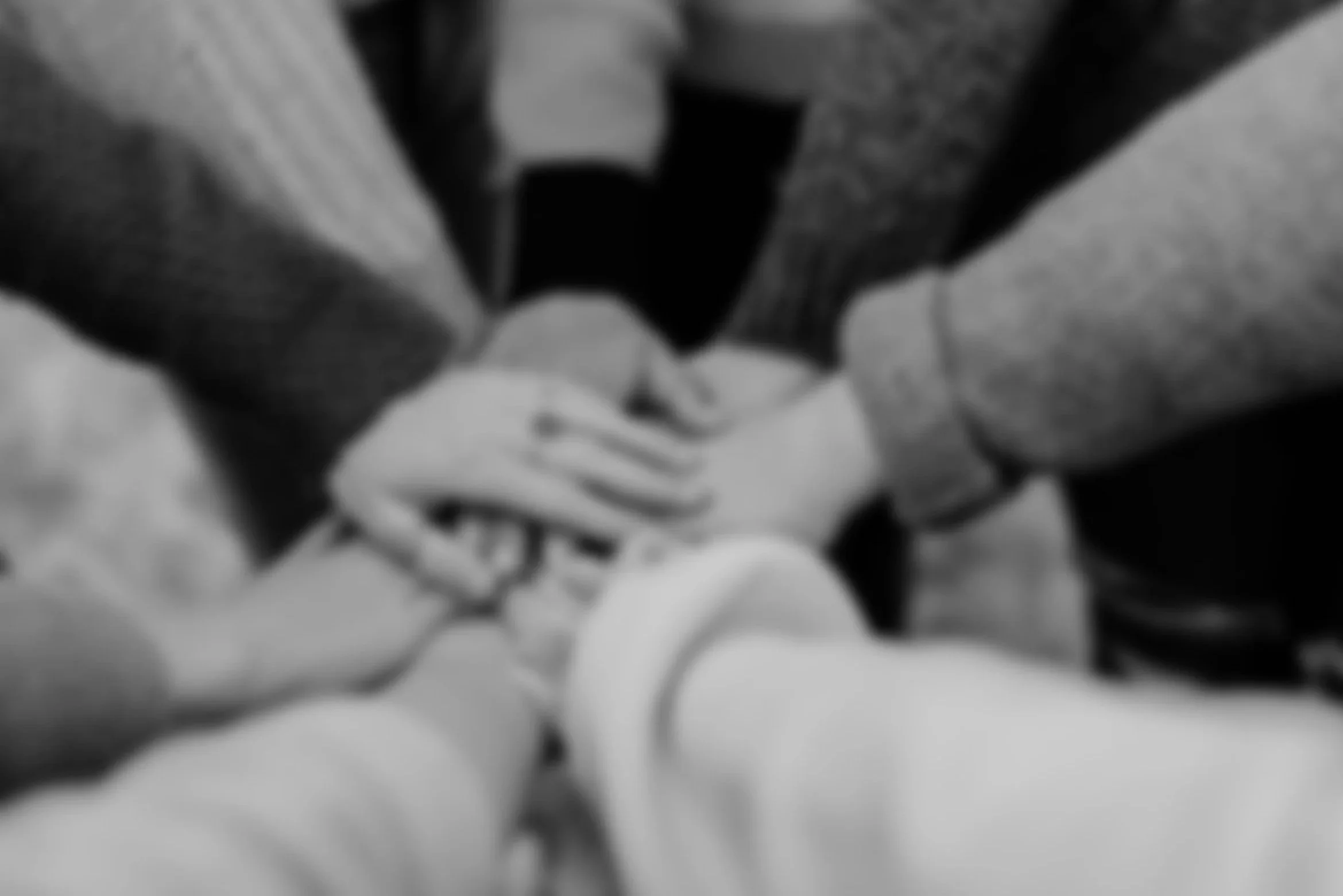 Black and white photo of two people holding hands, with one person wearing a long-sleeved shirt and the other wearing a bracelet.