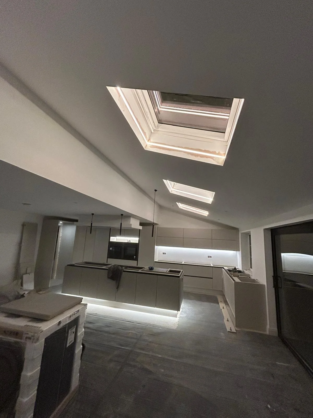 Modern kitchen with recessed skylights, white cabinetry, and a sliding glass door.