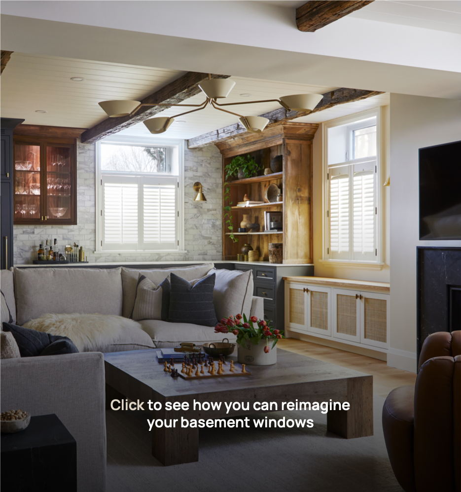 A cozy living room with a gray couch, wooden coffee table, and built-in cabinetry near the windows with white shutters, featuring decorative items and a TV mounted on the wall. Under window faux light with shutters.