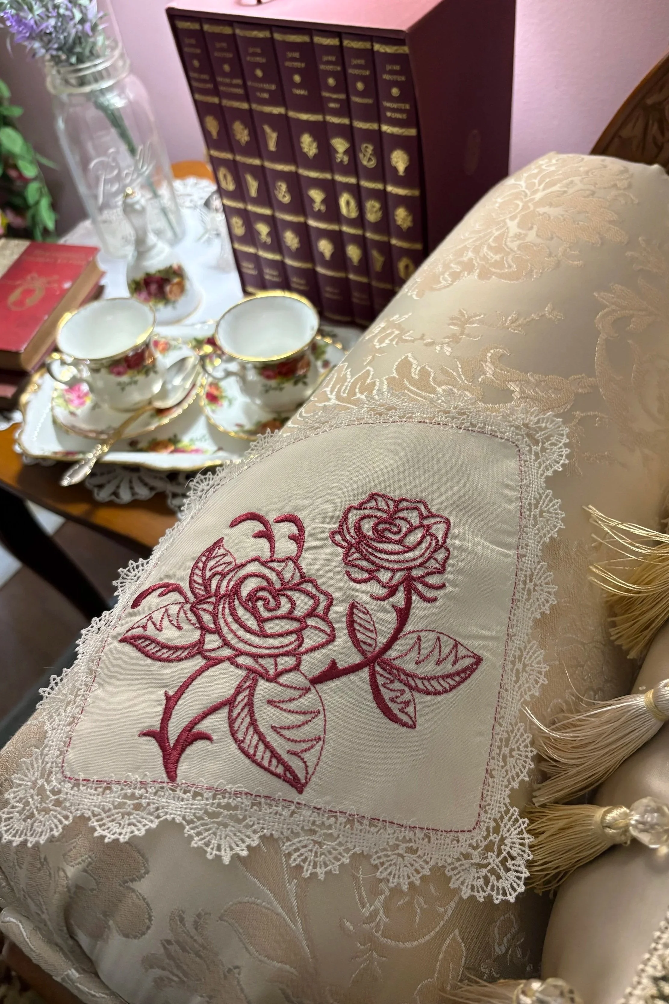Heirloom embroidered handkerchief featuring cranberry rose blossoms and delicate lace edging, displayed in a Victorian-inspired cottage setting.