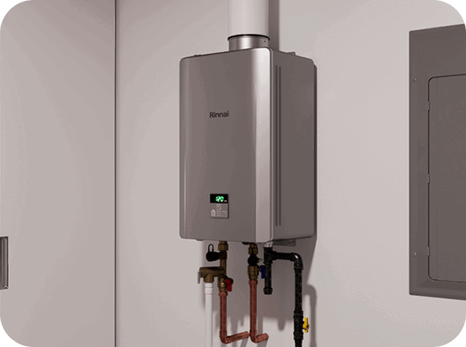A Rinnai tankless water heater installed on a wall in a utility closet with pipes connected below.