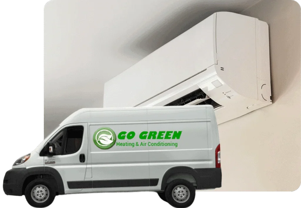 A white moving truck with a green logo and text reading "GO GREEN Heating & Air Conditioning" parked in front of an indoor wall-mounted air conditioner.