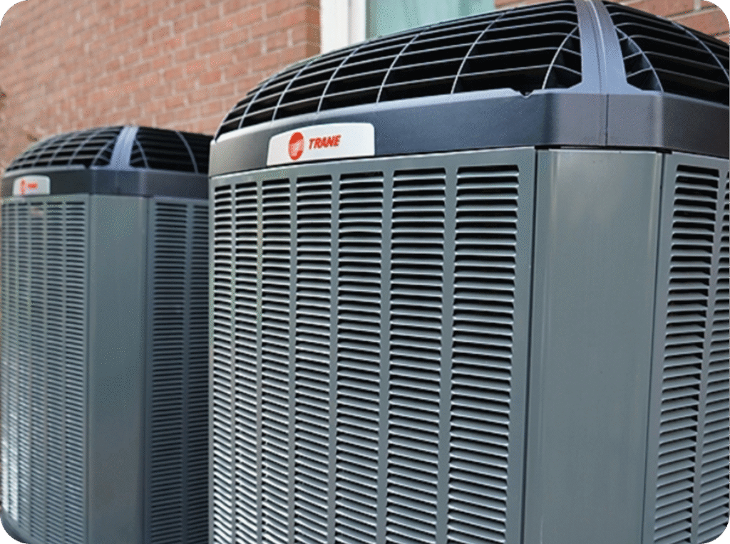 Two outdoor air conditioning units mounted on a brick wall